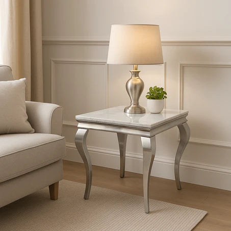 Silver side table with lamp and plant next to a beige armchair in a room with panelled walls.